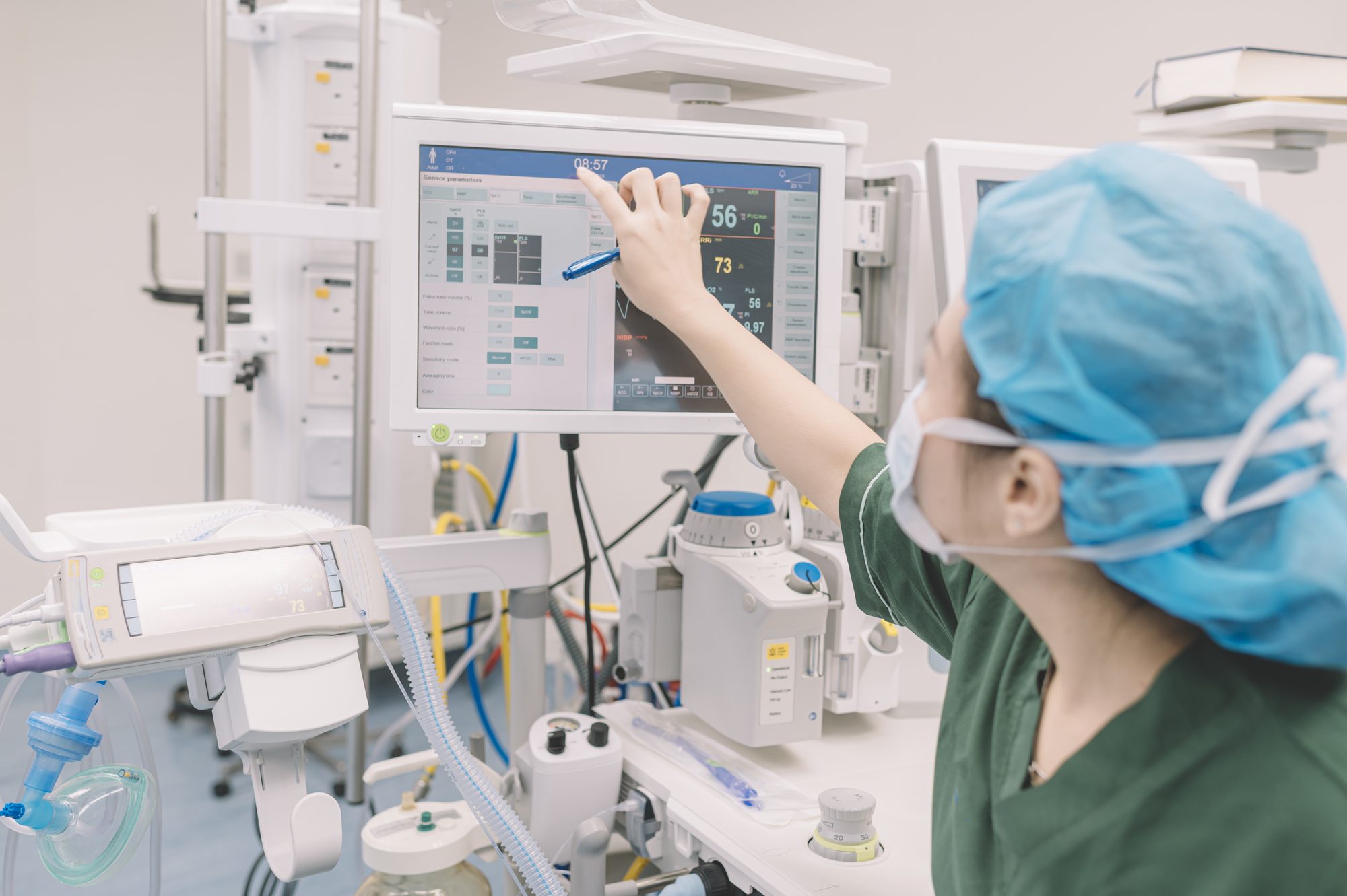 An anesthesiologist assistant adjusting a patient monitor in an operating room